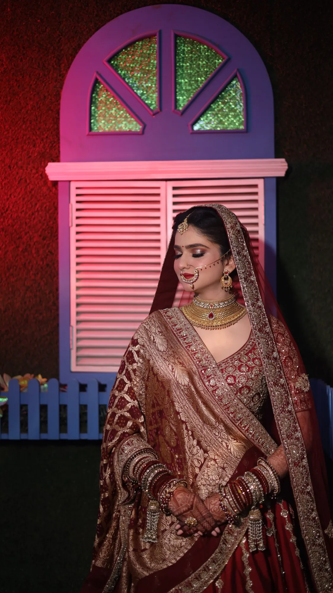 Bride in a maroon lehenga with gold jewellery