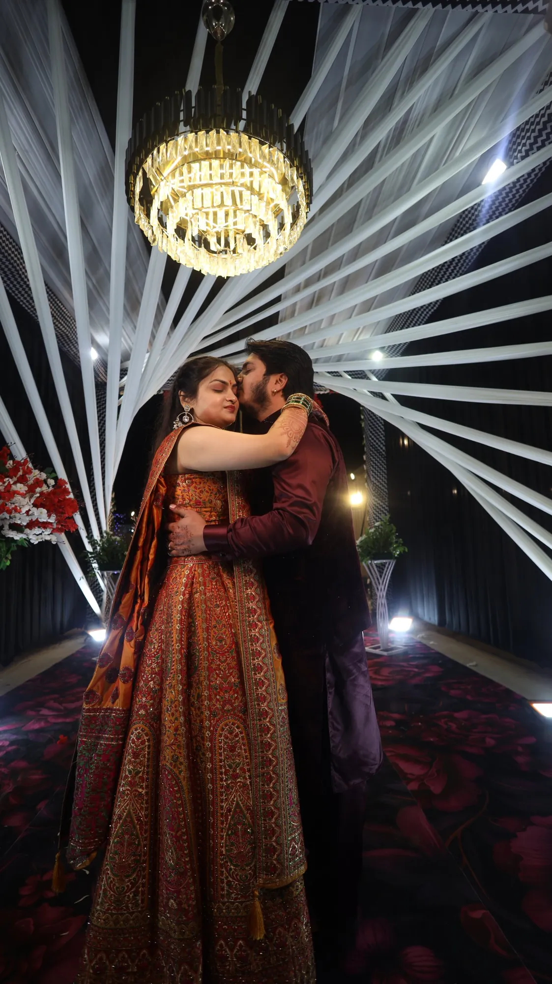 Bride and groom embracing under a crystal chandelier