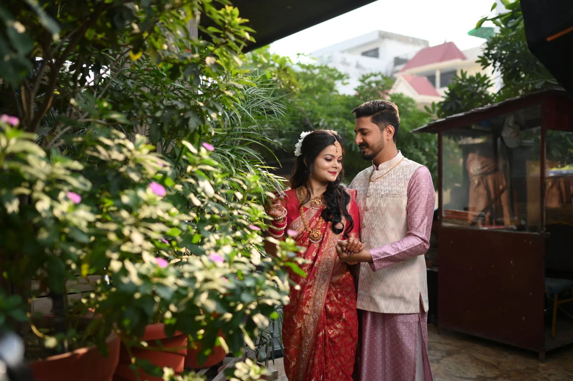 Newlywed couple in a red saree and kurta in a garden