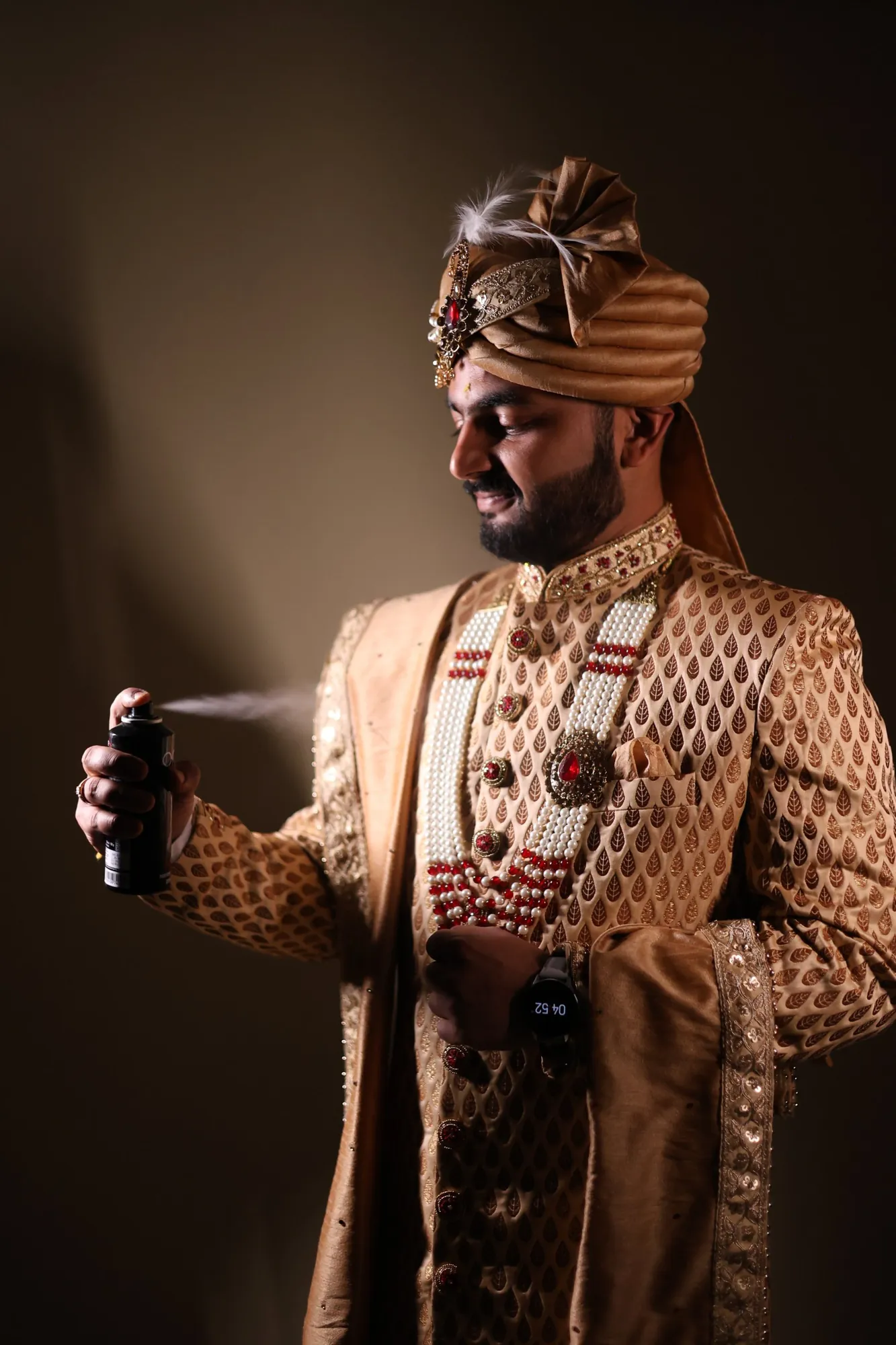 Groom getting ready in a gold sherwani and safa