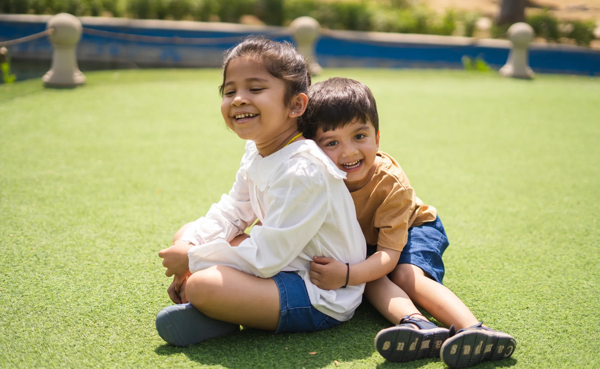 Brother and sister hugging and laughing on the lawn
