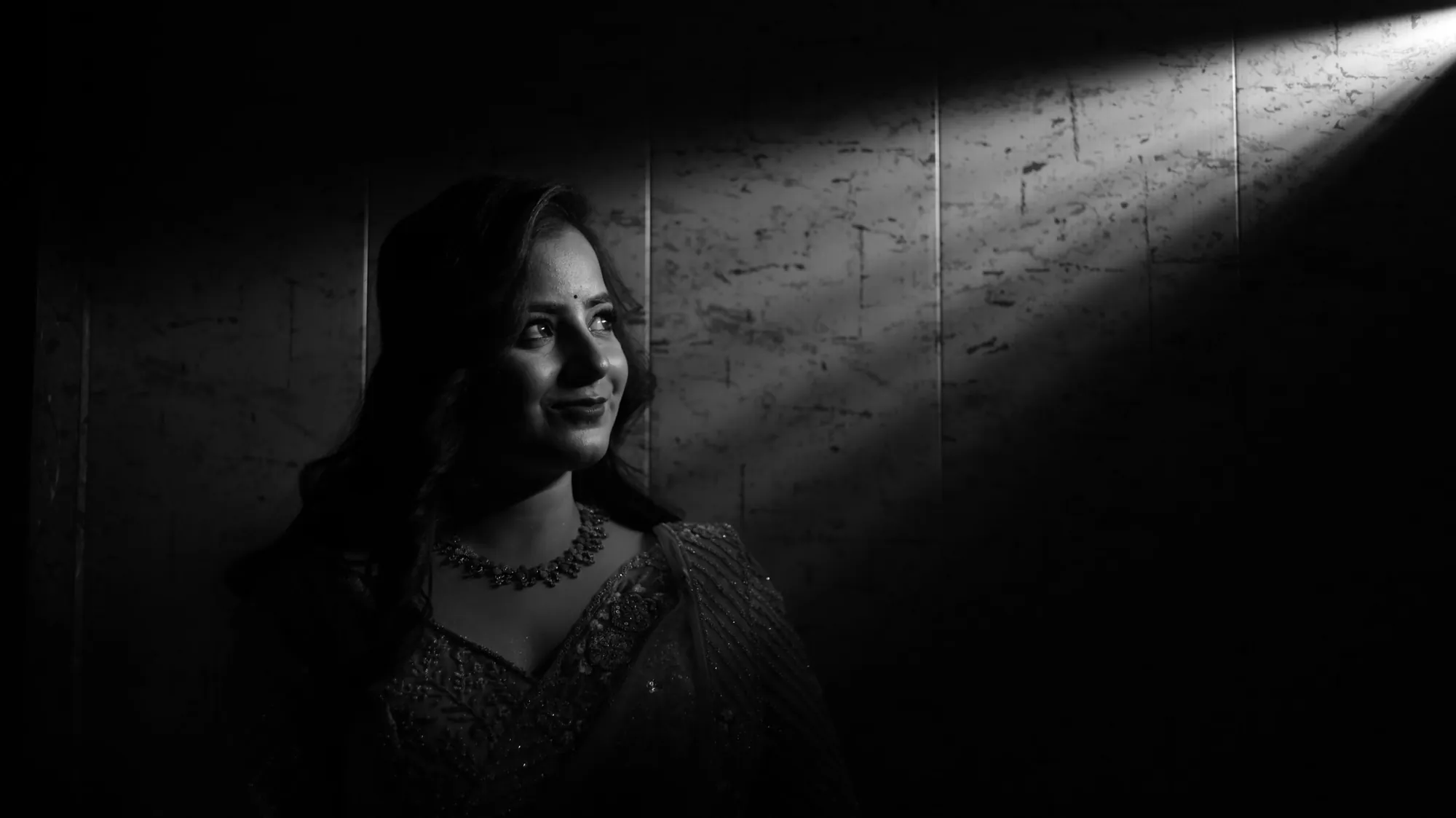Black-and-white portrait in a saree, sunbeam across the room