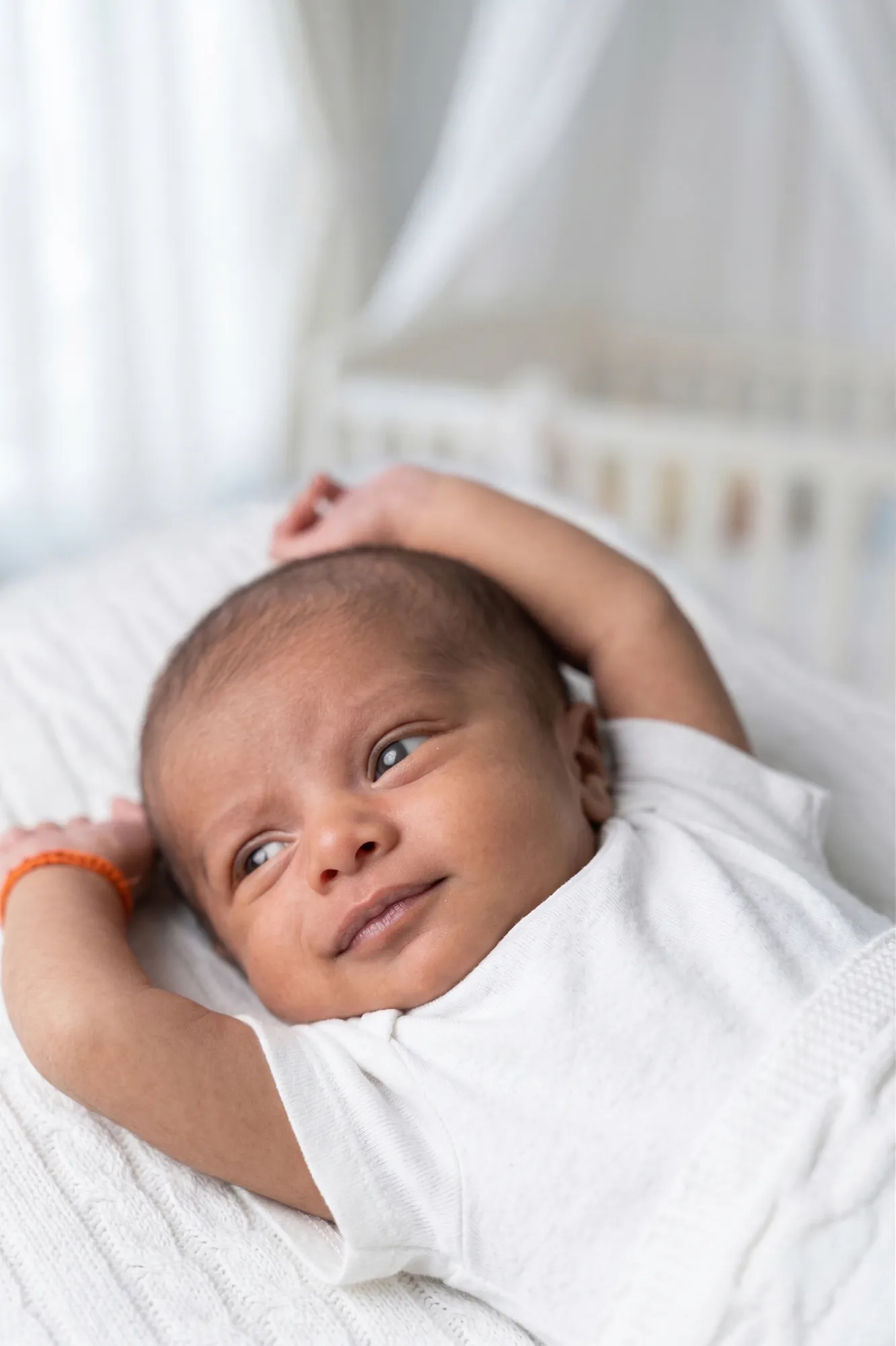 Newborn awake with arms stretched above his head