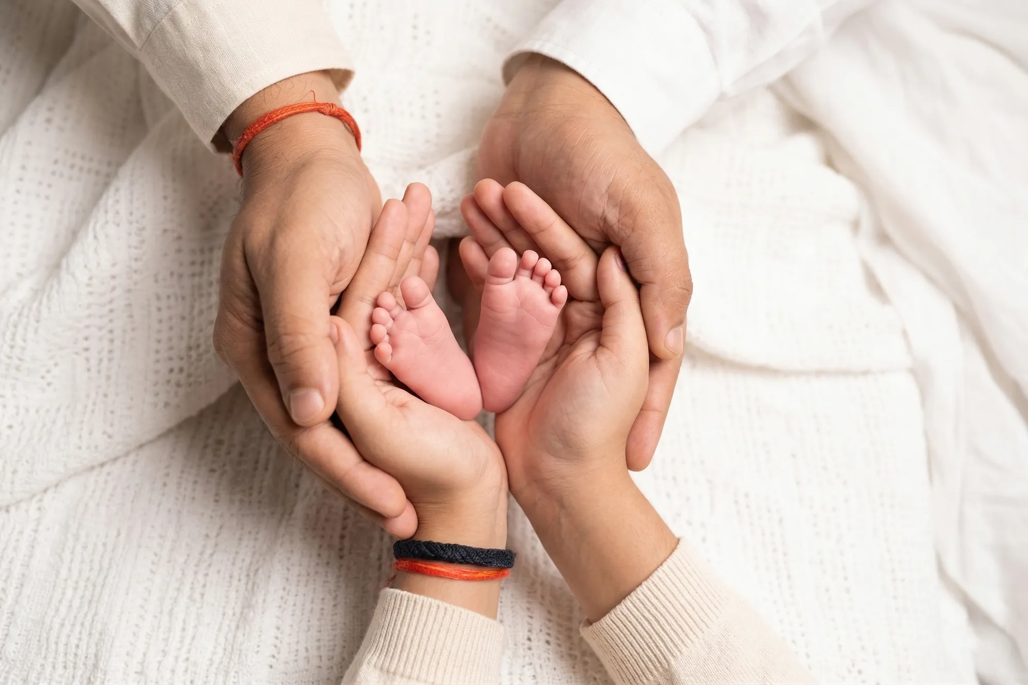 Newborn's tiny feet cradled in mum and dad's hands