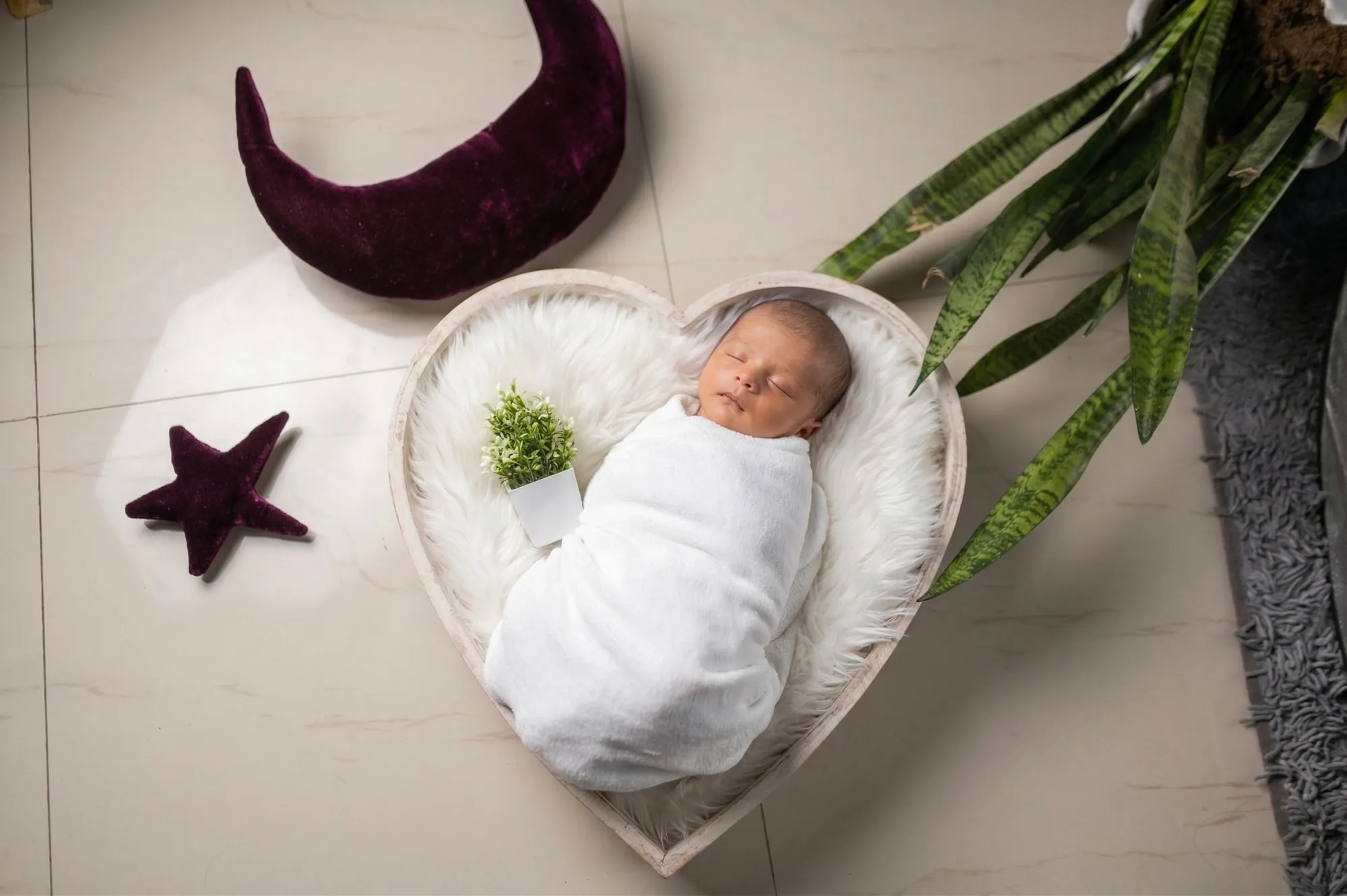 Newborn asleep in a heart-shaped bed with a moon and star