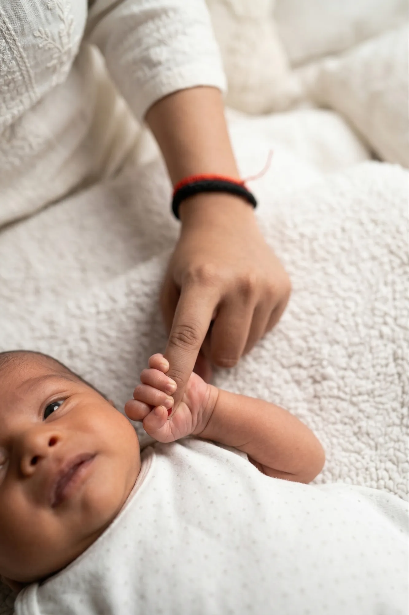 Newborn holding mum's finger