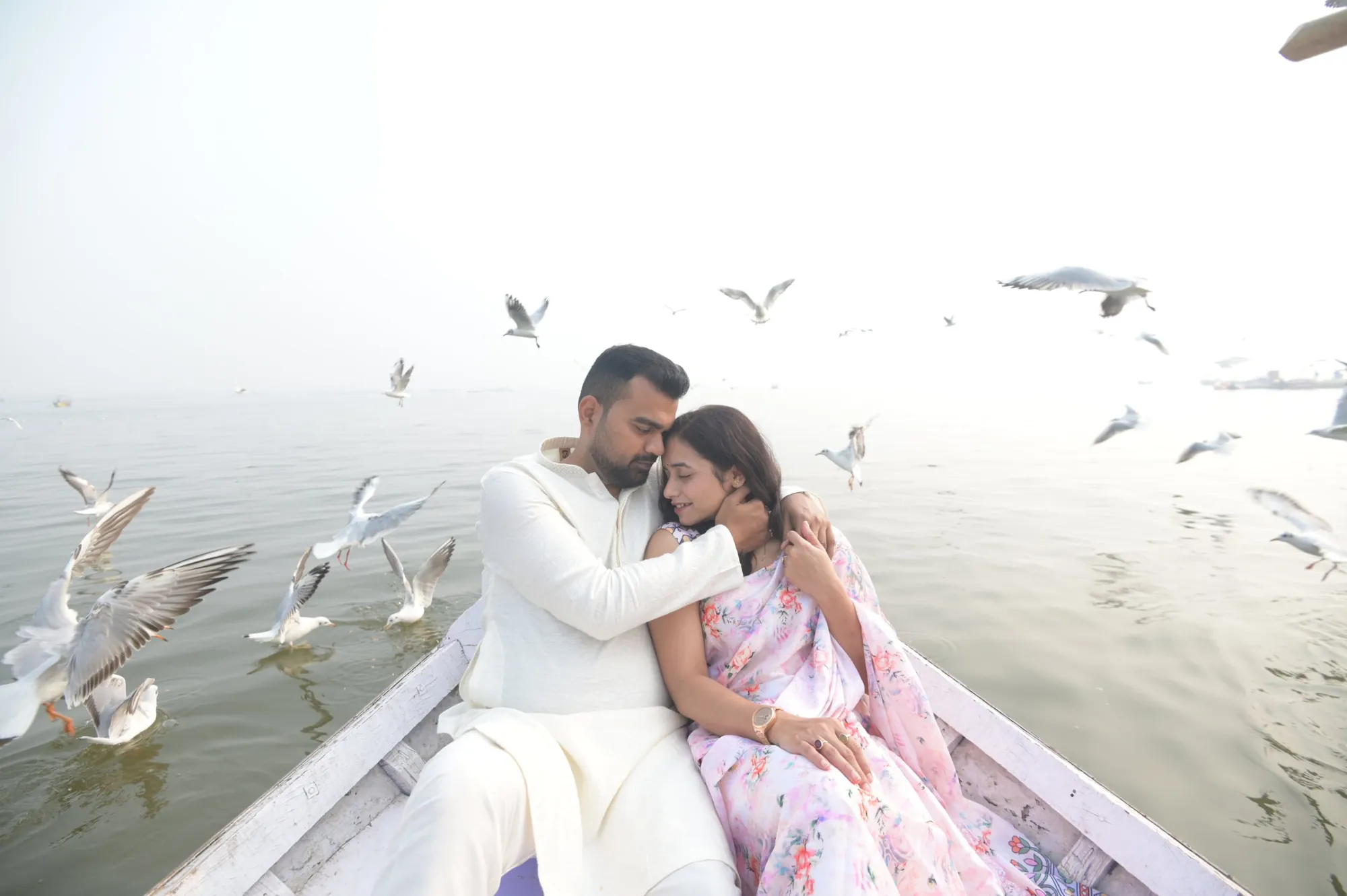 Couple in a boat surrounded by seagulls at the Sangam, Prayagraj